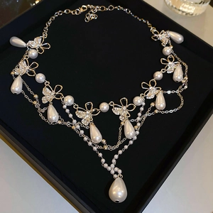 Detail of a layered butterfly necklace with waterdrop pearls and crystals on black velvet