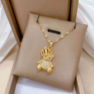 Luxurious 18K gold teddy bear crown necklace with white zircon pavé on beige jewelry stand