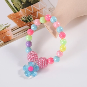 Detail of colorful children's pearl bracelet with pink textured beads and blue flower charm
