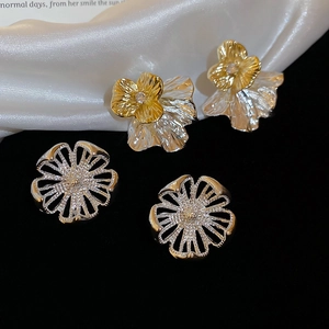 Details von hohlen Blumenohrringen aus Metall mit Kristall auf elegantem schwarzen Grund