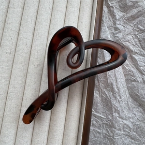 Detail of dark brown tortoiseshell heart claw clip on beige corduroy and paper