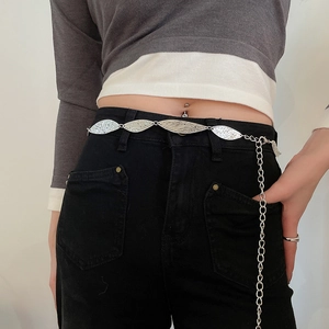 Detail of silver hammered metal leaf waist chain styled on black jeans and grey top