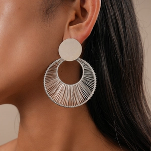 Close-up of a large silver hollow circular woven earring worn on a female model