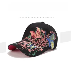 Dettaglio del ricamo a farfalla colorata e tesa rosa su un cappellino nero