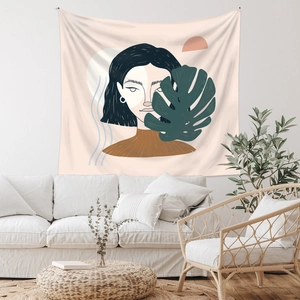 Artistic bohemian tapestry showing female portrait and monstera leaves in a living room