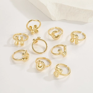 Detailed arrangement of gold adjustable balloon letter rings on a white stone background