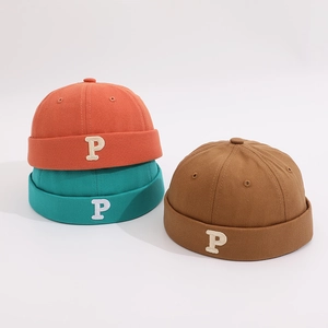Detailed macro view of vintage cotton brimless docker hats in orange, green, and brown colors