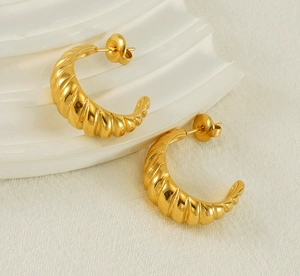 Macro detail of 18K gold plated crescent earrings with elegant textured spiral patterns
