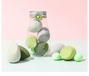 Detailansicht von grünen, weißen und grauen Make-up-Schwämmen in einer Gänseblümchen-Dose