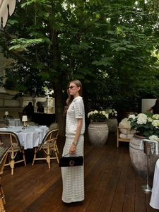 Detail of white knit polo top and hollow-out lace skirt for a sophisticated resort look