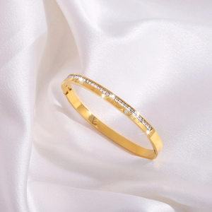 Macro detail of gold-plated stainless steel bangle with single row cubic zirconia and Roman numerals