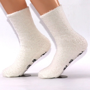 Detail of white coral fleece socks featuring black anti-slip lettering on the bottom sole