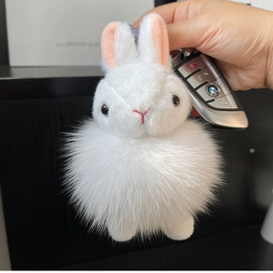 Detail of white plush bunny keychain with fluffy fur texture held near a car key