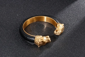 Detail view of a men's punk gold lion head open cuff bracelet with black leather texture