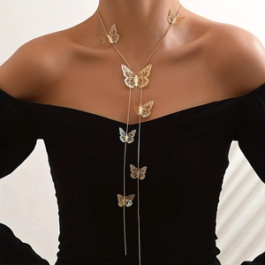 Detailed view of long gold tassel necklace with hollow butterfly charms on a black dress
