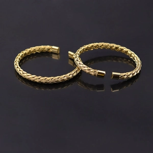 Minimalist stainless steel woven open cuff bracelet with gold finish on black surface