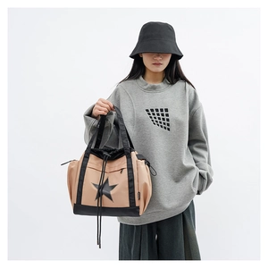 Detail view of khaki and black shoulder bag featuring drawstring closure and star patch