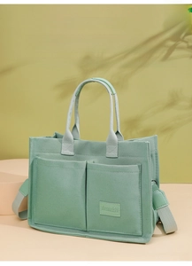 Detail of mint green canvas tote bag showing front pockets and durable strap texture