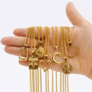 Close-up of seven assorted 18K gold-plated stainless steel necklaces held in a palm.