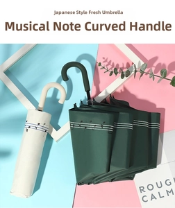 Detail of J-handle umbrellas with music note prints in cream and dark green colors