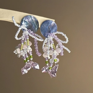 Detail of beaded tassel earrings with purple crystals and shell discs on display