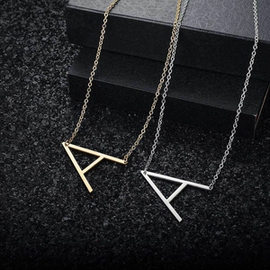 Macro detail of gold and silver initial A pendant necklaces on a black display surface