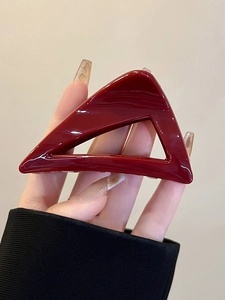 Close-up of a glossy deep red triangle hair claw clip in a minimalist geometric design