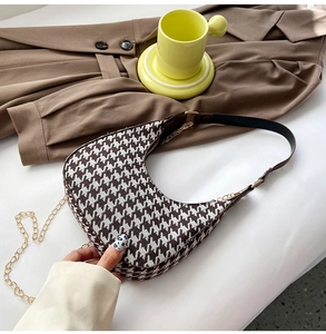 Close-up of houndstooth crescent bag with brown leather trim and golden chain detail