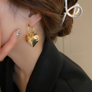 Nahaufnahme eleganter goldener Herzohrringe an einem Model mit poliertem Finish