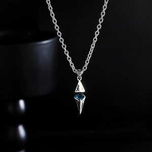 Macro view of silver starburst pendant with blue gemstone on O-chain necklace
