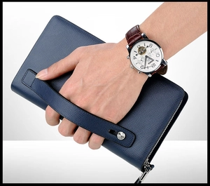 Close-up of deep blue Saffiano leather men's clutch bag with wrist strap and metal rivet