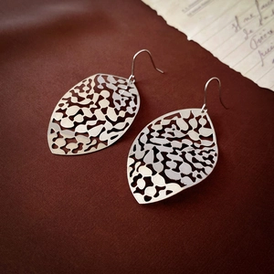Macro shot of silver hollow leaf tassel earrings with detailed metal texture and hook design