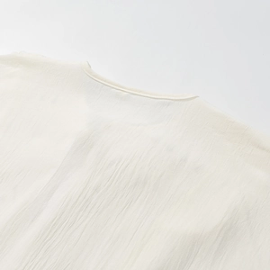 Detailed close-up of white linen shirt neckline showing fine stitching and fabric texture
