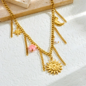Golden cuban chain necklace with sun moon star and pink flower charms on stone background