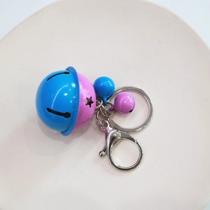 Close-up of colorful cartoon bells on a woven rope keychain in a white ceramic dish