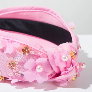 Détails d'un serre-tête rose en tissu avec fleurs 3D, paillettes et perles