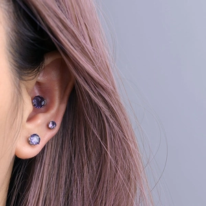 Three purple round cubic zirconia magnetic stud earrings set in silver steel on ear