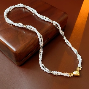 Macro view of woven faux pearl and silver bead necklace with golden heart magnetic clasp