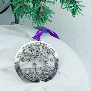 Detail of silver tree of life memorial ornament with purple ribbon and engraved quote