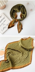 Close-up of pleated silk scarf featuring green and red floral patterns and texture