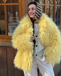 Close-up of fluffy yellow faux fur jacket texture and fiber details on a woman outfit