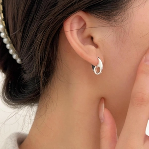 Close-up of minimalist silver hoop earrings and pearl hair clips worn by a model