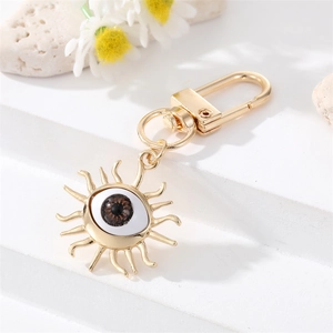 Detail of golden Evil Eye keychain with brown resin sunburst charm on white steps