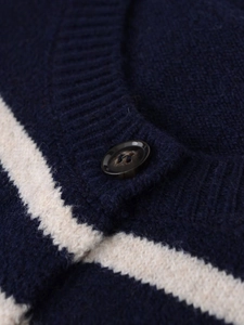 Detail of navy striped knit cardigan featuring a textured tortoiseshell button and soft fabric