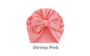 Detailed view of shrimp pink baby turban hat with a large bow made of soft knit cotton