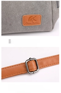 Detail of gray canvas bag featuring leather brand tag and adjustable metal buckle strap