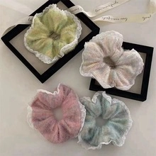 Close-up of four assorted pastel hair scrunchies with white lace trim in flat lay view