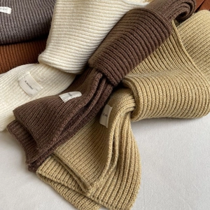 Detailed close-up of winter knit scarves texture with brand labels in earthy tones