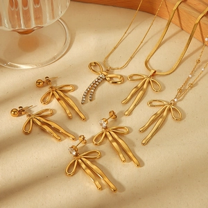 Golden bow jewelry set featuring necklaces and earrings with rhinestones on linen fabric