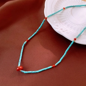 Detail of bohemian necklace with turquoise tube beads and red round stone accents